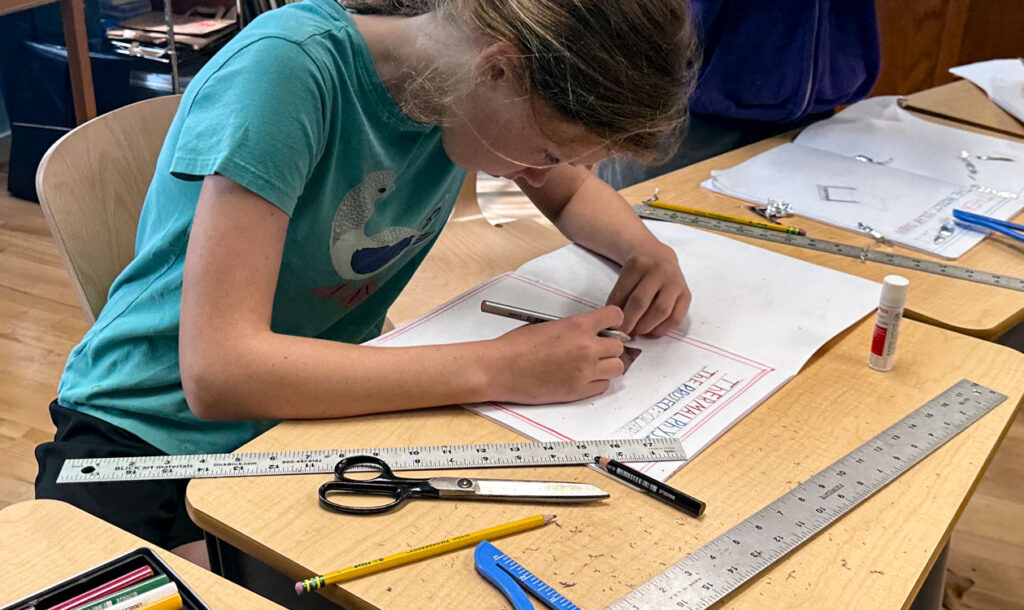 Middle school student working on school work with pencil, scissors, and t-square