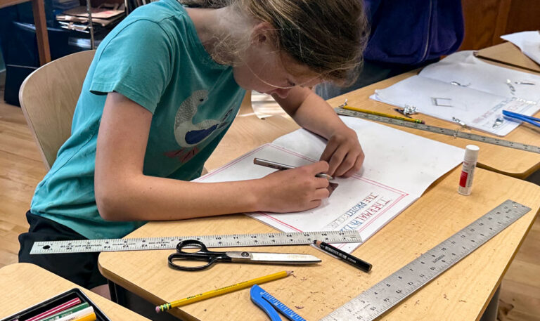 Middle school student working on school work with pencil, scissors, and t-square