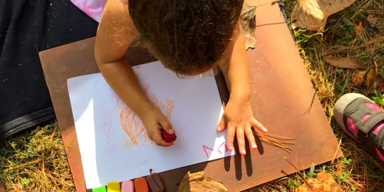 overhead view of young child drawing in the sunlight