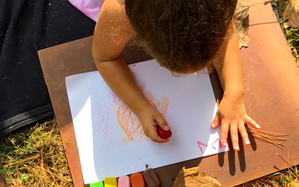 overhead view of young child drawing in the sunlight