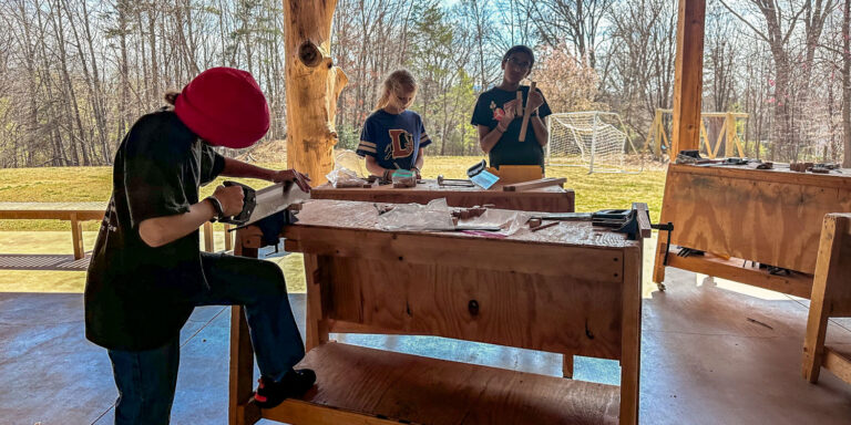 Middle school students sawing wood on a sunny day
