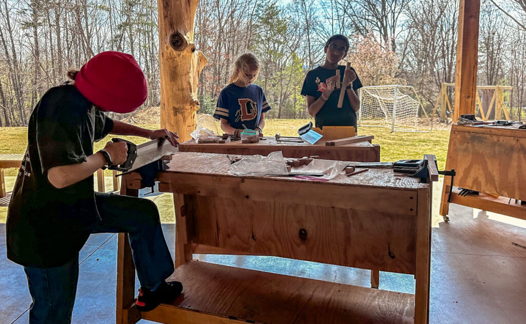 Middle school students sawing wood on a sunny day