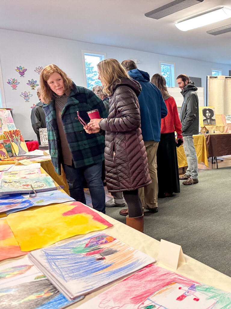 adults looking at student work for friends and family day at CHarlottesville Waldorf School