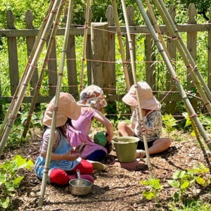 early childhood students sitting in a bean pole tent