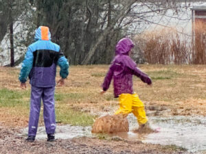 students splashing in a rain puddle