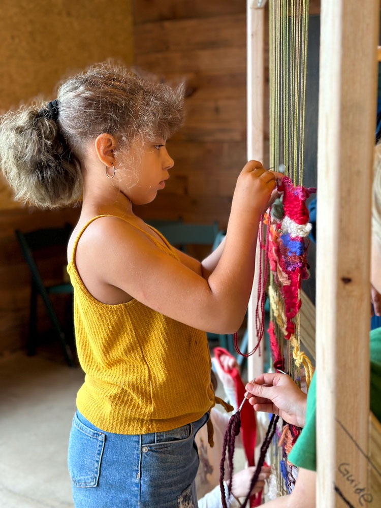 student working on stand up weaving loom