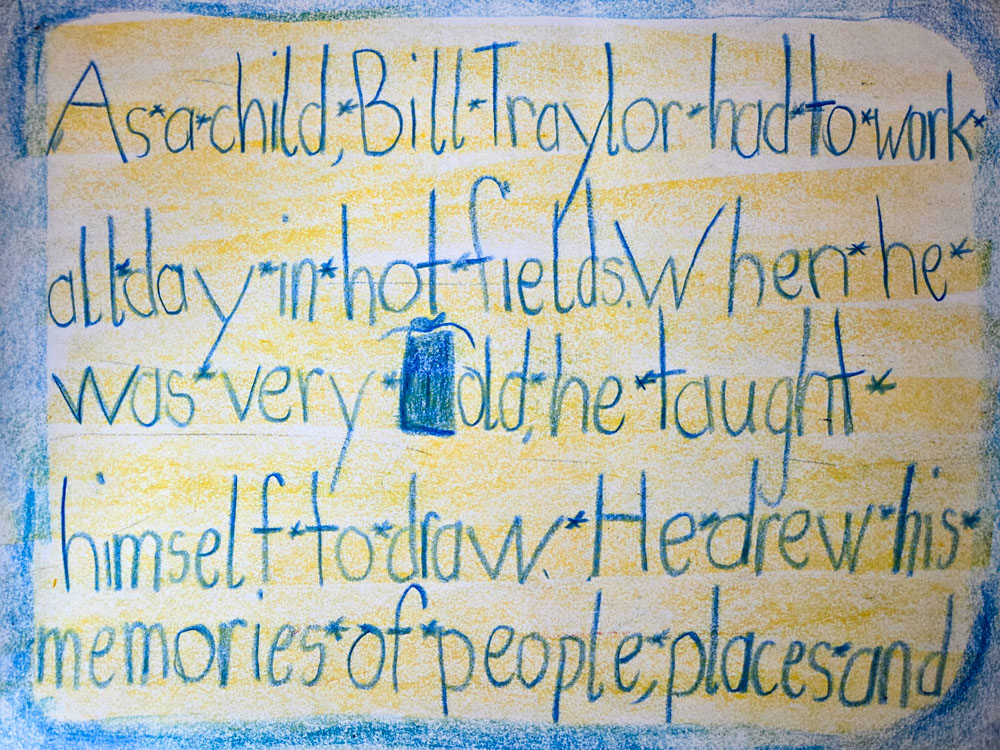 First grade student writing about artist Bill Traylor in large crayon letters on paper