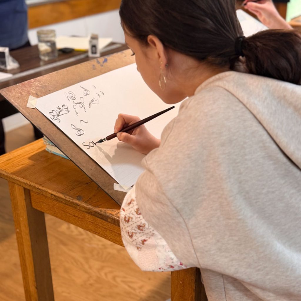 cws 7th grade student working on calligraphy lettering with an ink pen