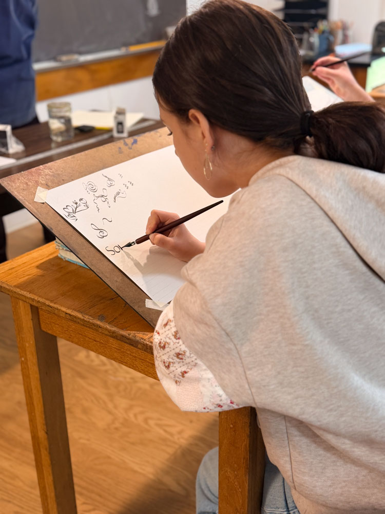 cws 7th grade student working on calligraphy lettering with an ink pen