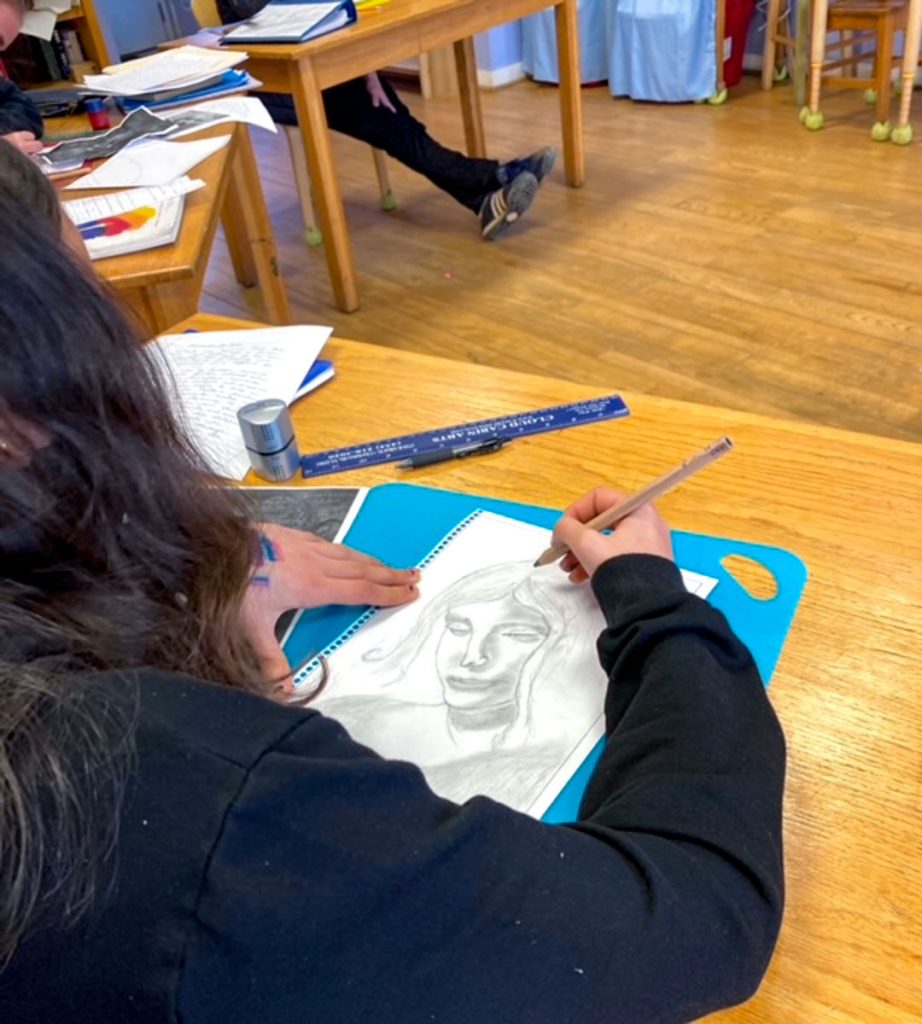 Overshoulder shot of a middle school student sketching a Leonardo DaVinci drawing with pencil