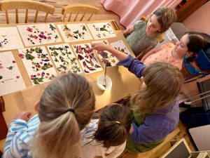 Toddlers and their teacher working on flower petal art at Charlottesville Waldorf School(CWS) in the Playgarden
